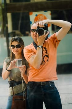 Mid adult man and a young woman taking photographs