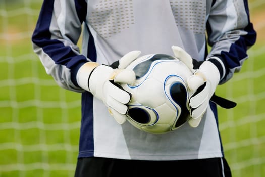 Mid section view of a goalie holding a soccer ball