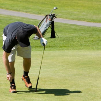 Person bending holding a golf ball and a golf club