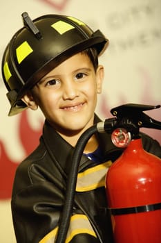 Portrait of a boy dressed as a firefighter and holding a fire extinguisher