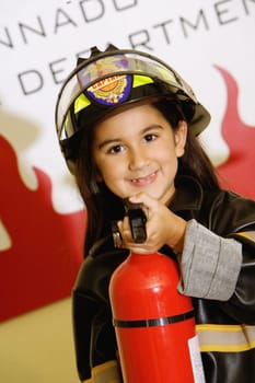Close-up of a girl dressed as a firefighter and holding a fire extinguisher