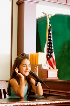 Girl imitating a witness sitting in a witness stand