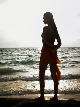 Side profile of a young woman standing on the beach