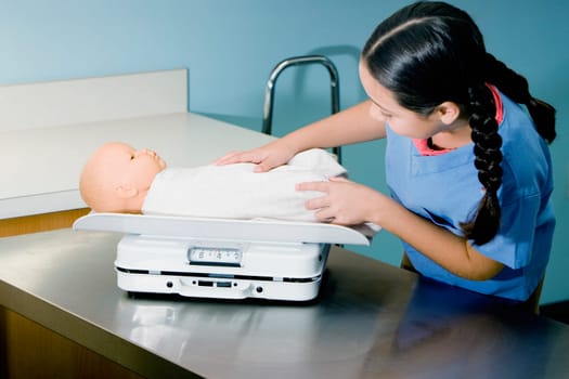 Girl weighing a doll on a weighing scale