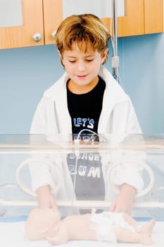 Close-up of a boy standing near an incubator