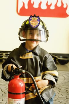 Close-up of a boy dressed as a firefighter and holding a fire extinguisher