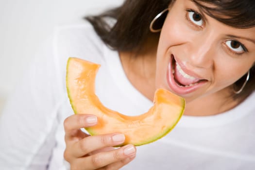 Portrait of a young woman eating a slice of melon