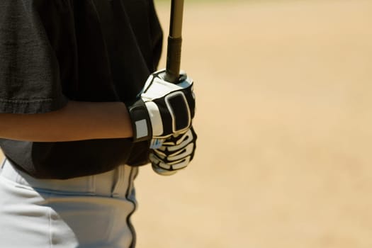 Mid section view of a boy holding a baseball bat