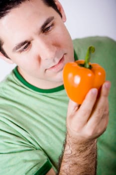 Close-up of a mid adult man holding an orange bell pepper