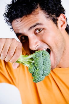 Portrait of a young man eating a broccoli