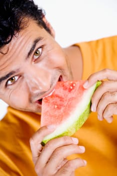 Portrait of a young man eating a slice of a watermelon