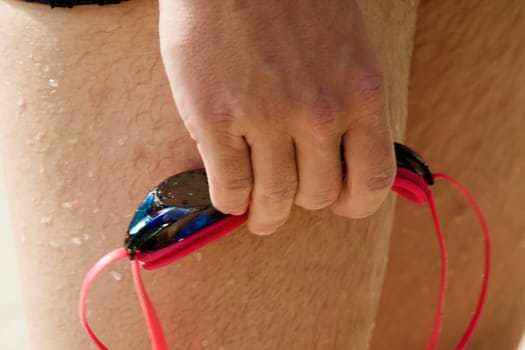 Close-up of a manŽs hand holding swimming goggles