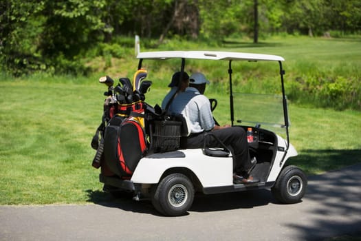 Side profile of two people sitting in a golf cart