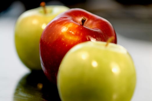 Close-up of two green apples and a red apple