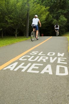 Rear view of two people cycling on the road