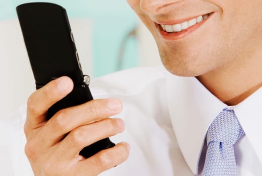Close-up of a businessman holding a mobile phone and smiling