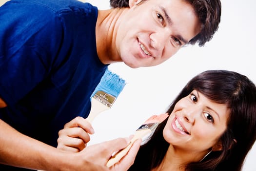 Portrait of a couple holding paintbrushes and smiling