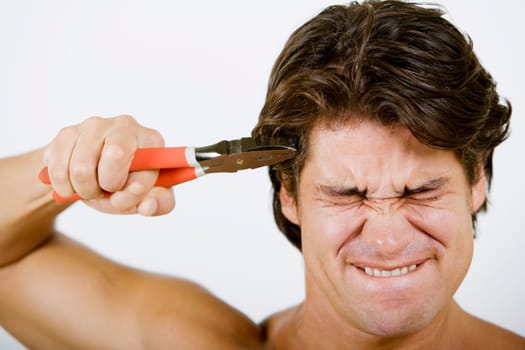 Close-up of a mid adult man pressing pliers up to his head