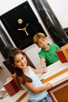 Portrait of a boy imitating a cashier at a bank giving money to a girl