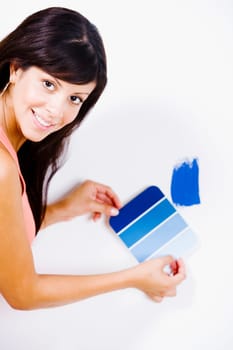 Portrait of a young woman holding a color swatch against a wall