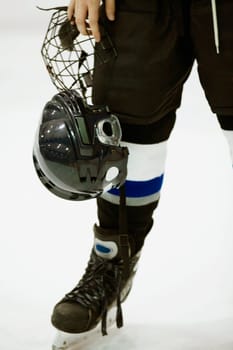 Low section view of an ice hockey player holding a helmet