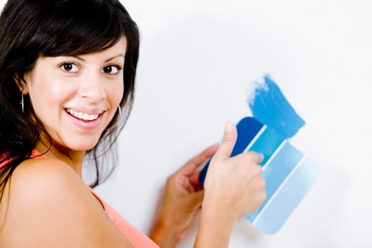 Portrait of a young woman holding a color swatch against a wall