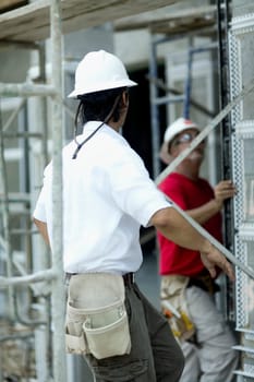 Side profile of a male architect working at a construction site with another male architect standing beside him
