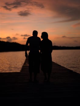 Silhouette of a man and a woman walking on a pier