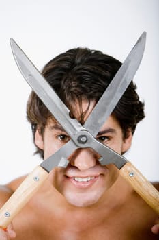 Portrait of a mid adult man holding a hedge clipper in front of his face