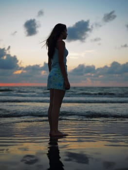 Side profile of a teenage girl standing on the beach