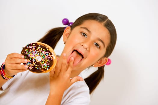 Portrait of a girl holding a donut and licking her finger