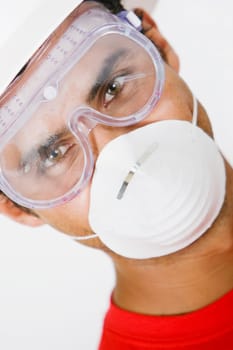Portrait of a young man wearing a hardhat with a pollution mask and a protective eyewear