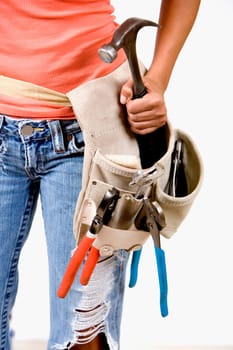 Mid section view of a person holding a hammer in a tool belt