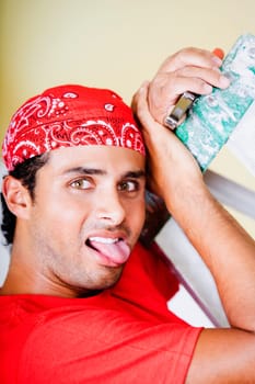 Portrait of a young man holding a pair of pliers and sticking his tongue out