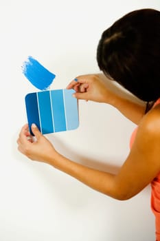 Woman holding a color swatch against a wall