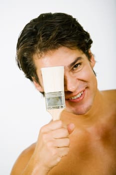 Portrait of a mid adult man holding a paintbrush in front of his face