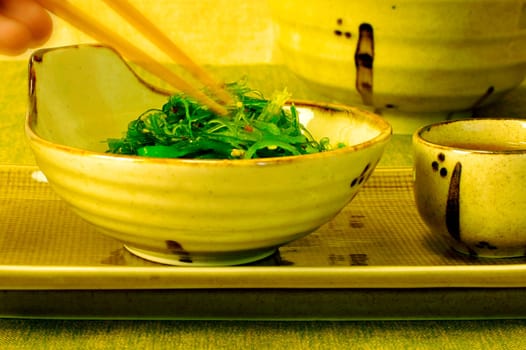 Close-up of a personŽs hand holding a pair of chopsticks in a bowl of salad