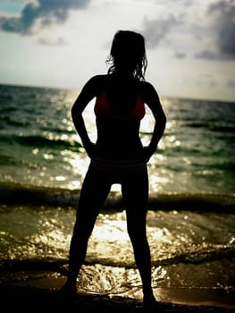 Silhouette of a young woman standing on the beach