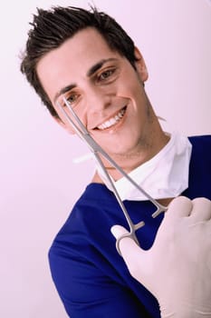 Portrait of a male surgeon holding a surgical scissors and smiling