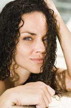 Portrait of a young woman leaning at the edge of a swimming pool