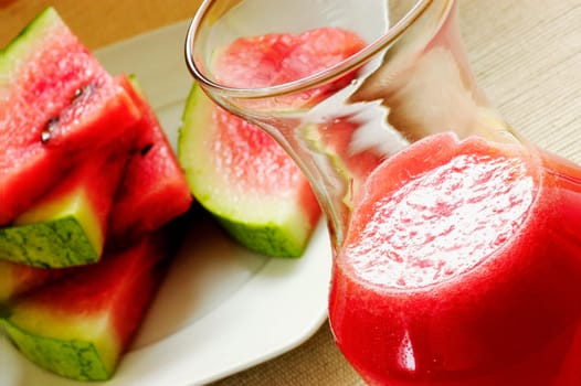 Close-up of slices of watermelon with a glass of juice