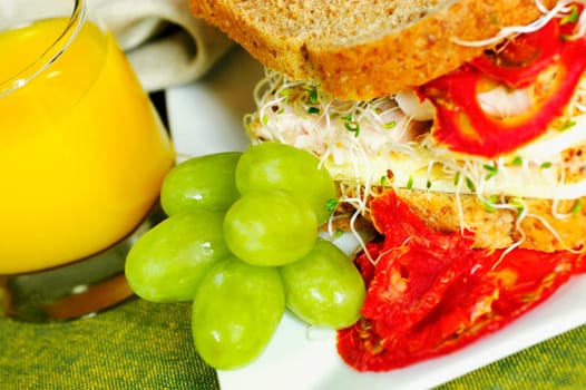 Close-up of a sandwich with a glass of juice and grapes
