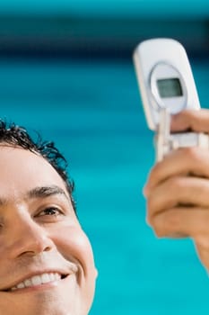 Close-up of a young man holding a mobile phone and smiling