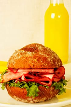 Close-up of a roast beef burger and a bottle of orange juice