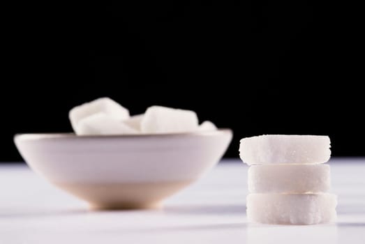 Stack of sugar cubes and a bowl of sugar cubes in the background