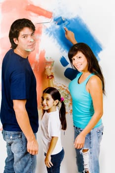Portrait of a young man and a mid adult woman with their daughter painting a wall