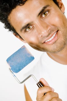 Portrait of a young man holding a paint roller and smiling
