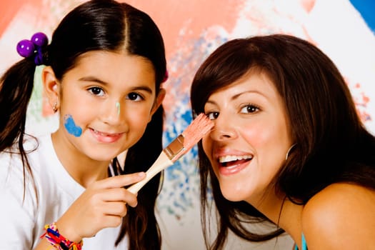 Portrait of a girl painting on her motherŽs nose