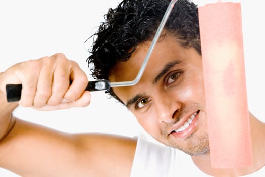 Portrait of a young man holding a paint roller and smiling