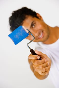 Portrait of a young man holding a paint roller and smiling